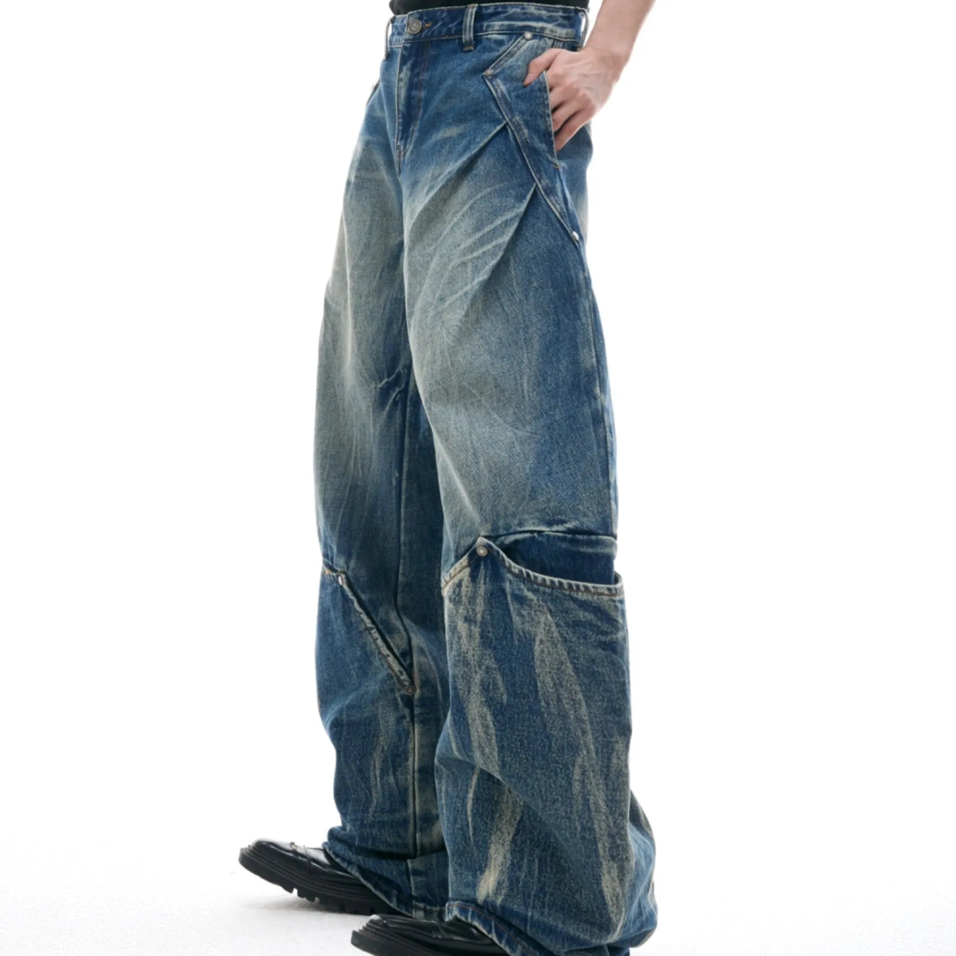 Man wearing verdant blue loose-fit jeans with curved seam detail and a vintage washed burst pattern.