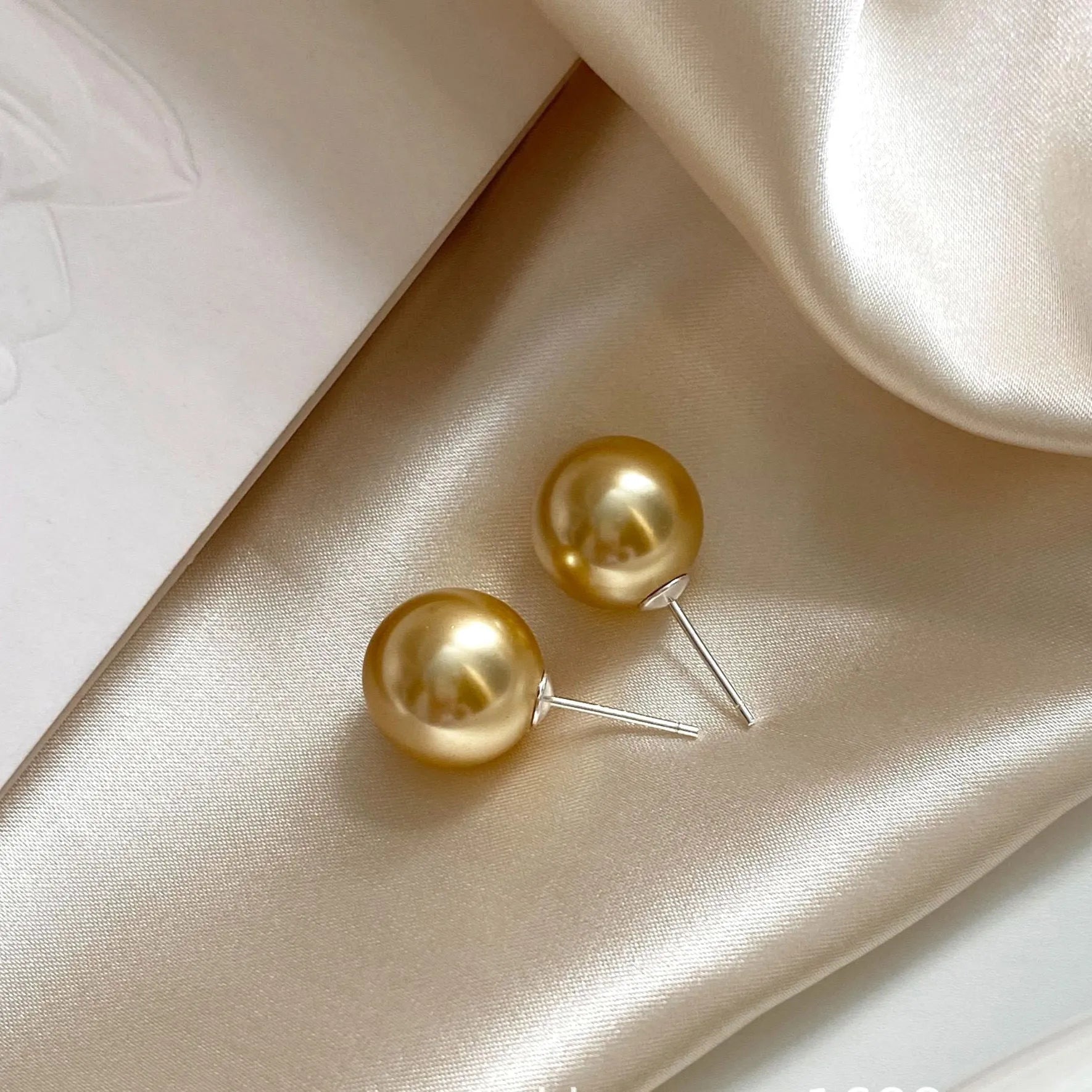 A pair of large geometric pearl stud earrings with a retro design on a silver setting.