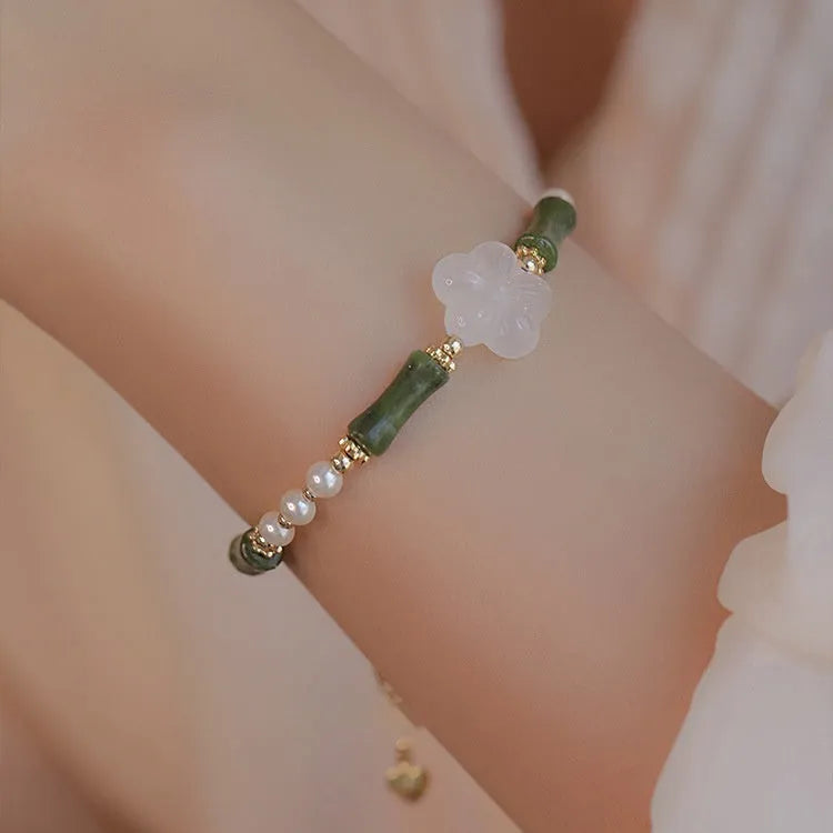 Close-up of a handcrafted Chinese antique style bracelet with bamboo joint design, featuring Hetian jade and 4mm shell pearls with copper details.