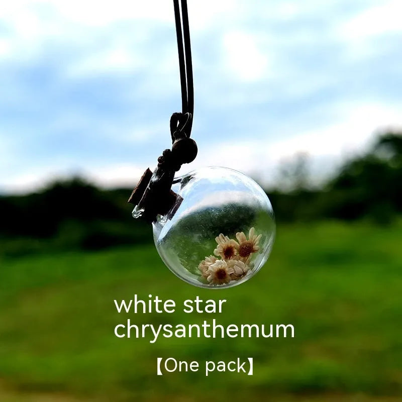 Glass car perfume pendant with preserved flowers inside, shown in a selection of different floral colours.