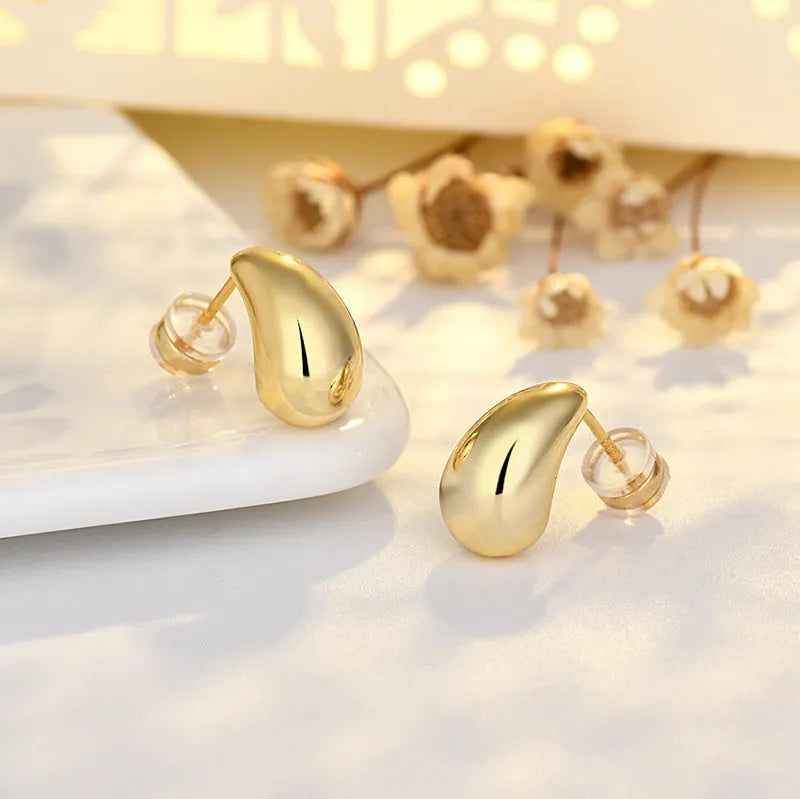 Minimalistic water drops earrings in gold plated copper, drop shape stud style on white background