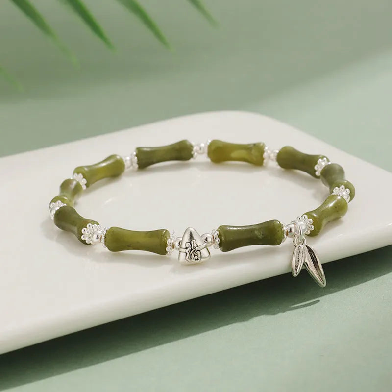 Women's green aventurine crystal bracelet with bamboo, strawberry quartz, and jade beads on wrist.