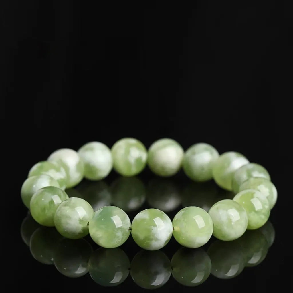 Green milk-in-water Xiuyan jade bracelet with polished geometric beads on a wrist.