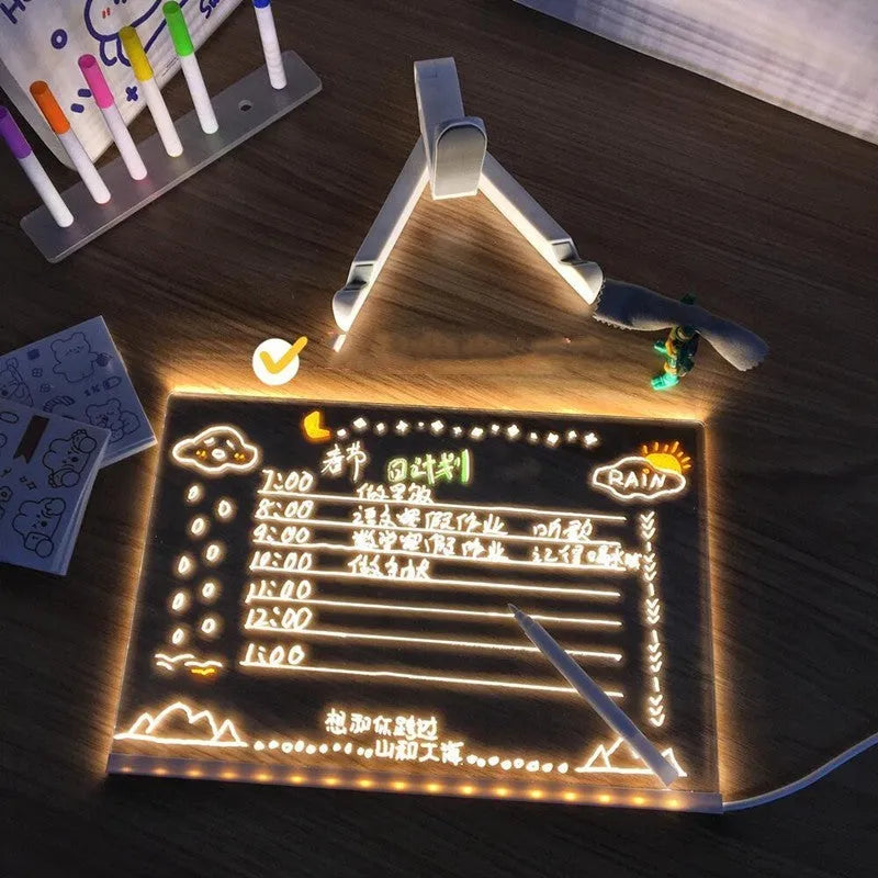 DIY acrylic LED message board on a desk with handwritten notes, glowing softly, next to colourful pens.