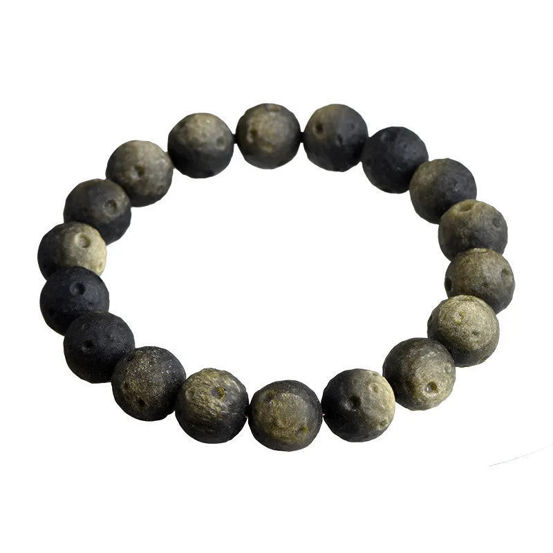 Natural obsidian crater ball bracelet in gold or silver stone colour on a wrist, showing textured bead surface.