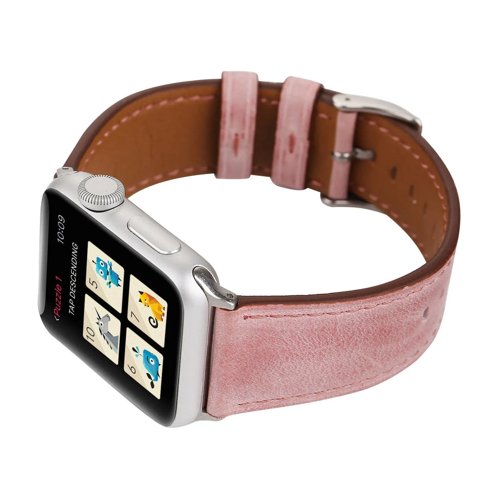 Leather watch strap with a metal folding buckle on a wooden surface.