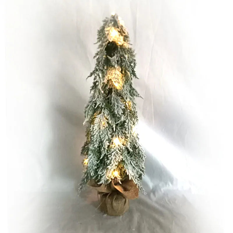 Small 24-inch white artificial Christmas tree with LED lights and snow effect on a desktop