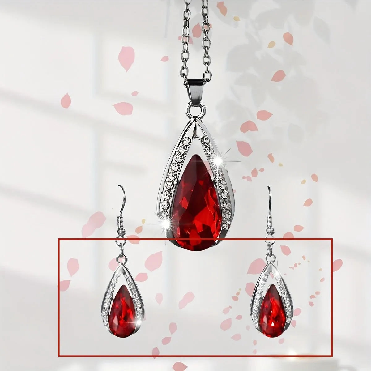 Black and red teardrop-shaped glass pendant necklace and matching earrings set laid flat.