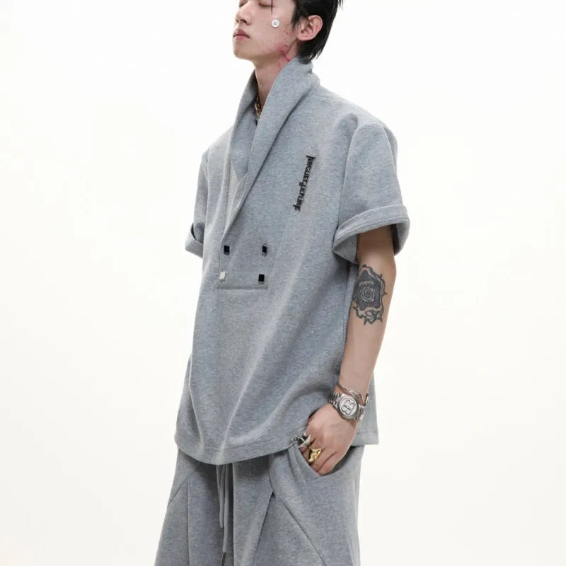 Men's dark grey V-neck padded shoulder short sleeve jacket with metal embellishments and matching shorts.