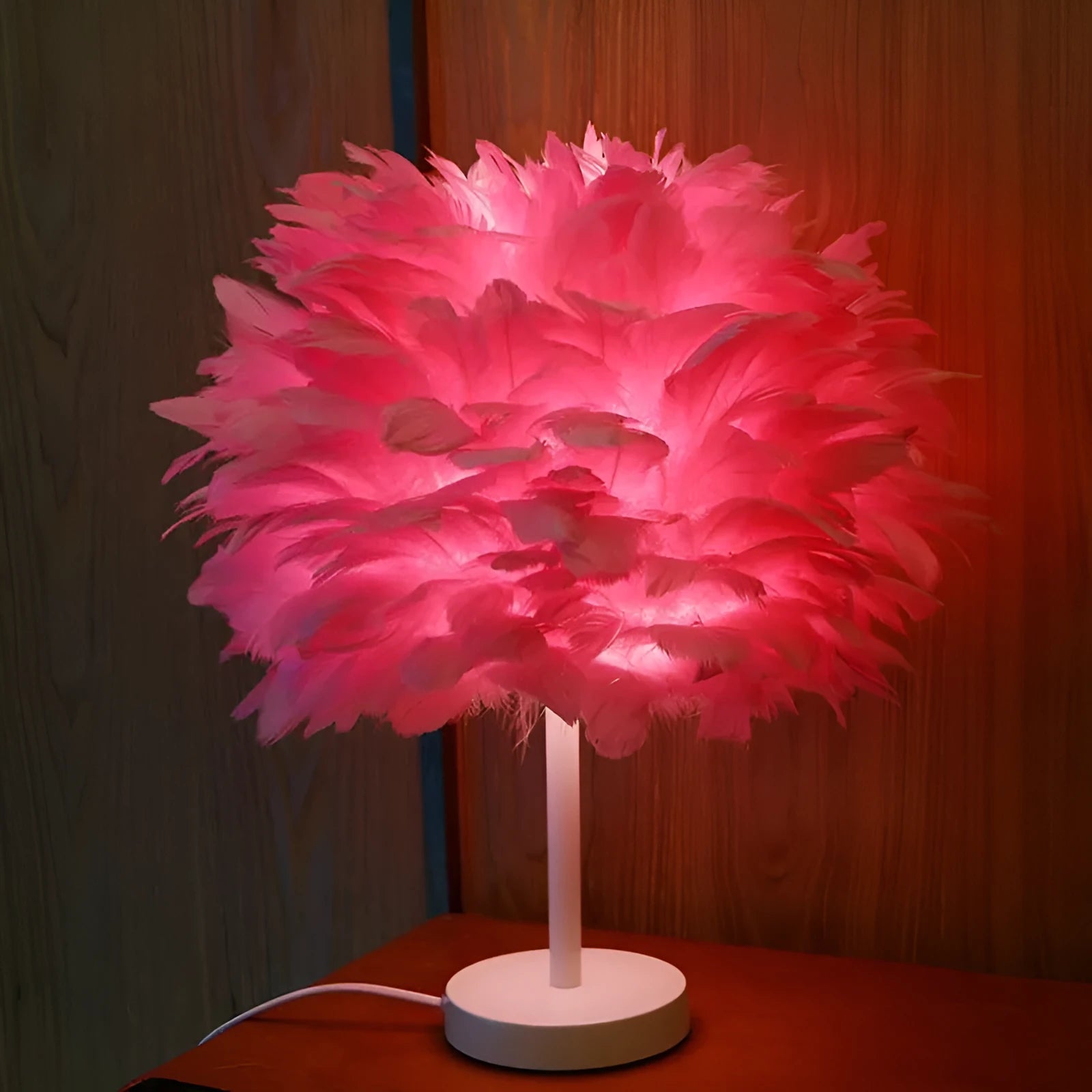 Handmade feather table lamp with metal base, white feathers, and remote control on a wooden bedside table
