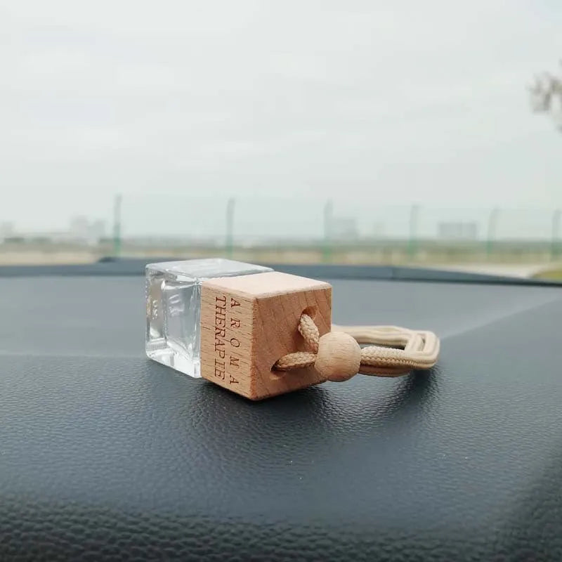 Square clear glass car fragrance pendant bottle with 8ml capacity hanging from a rearview mirror
