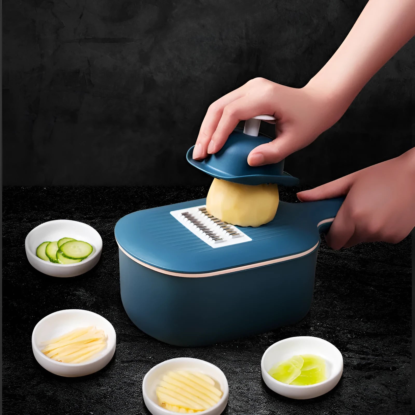 Dark blue manual vegetable cutter with four blades, hand guard, and drain basket on a kitchen counter