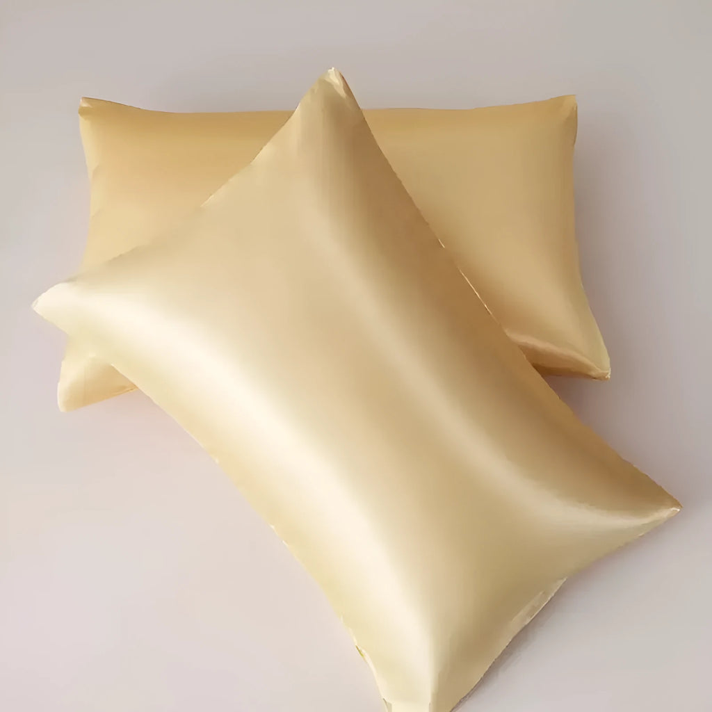 A pair of solid colour satin cloth pillowcases in a choice of sizes on a bed.