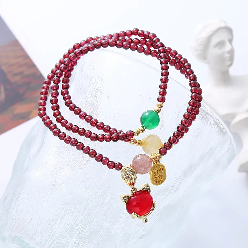 Purplish red adjustable rope bracelet with a detailed natural garnet fox charm.