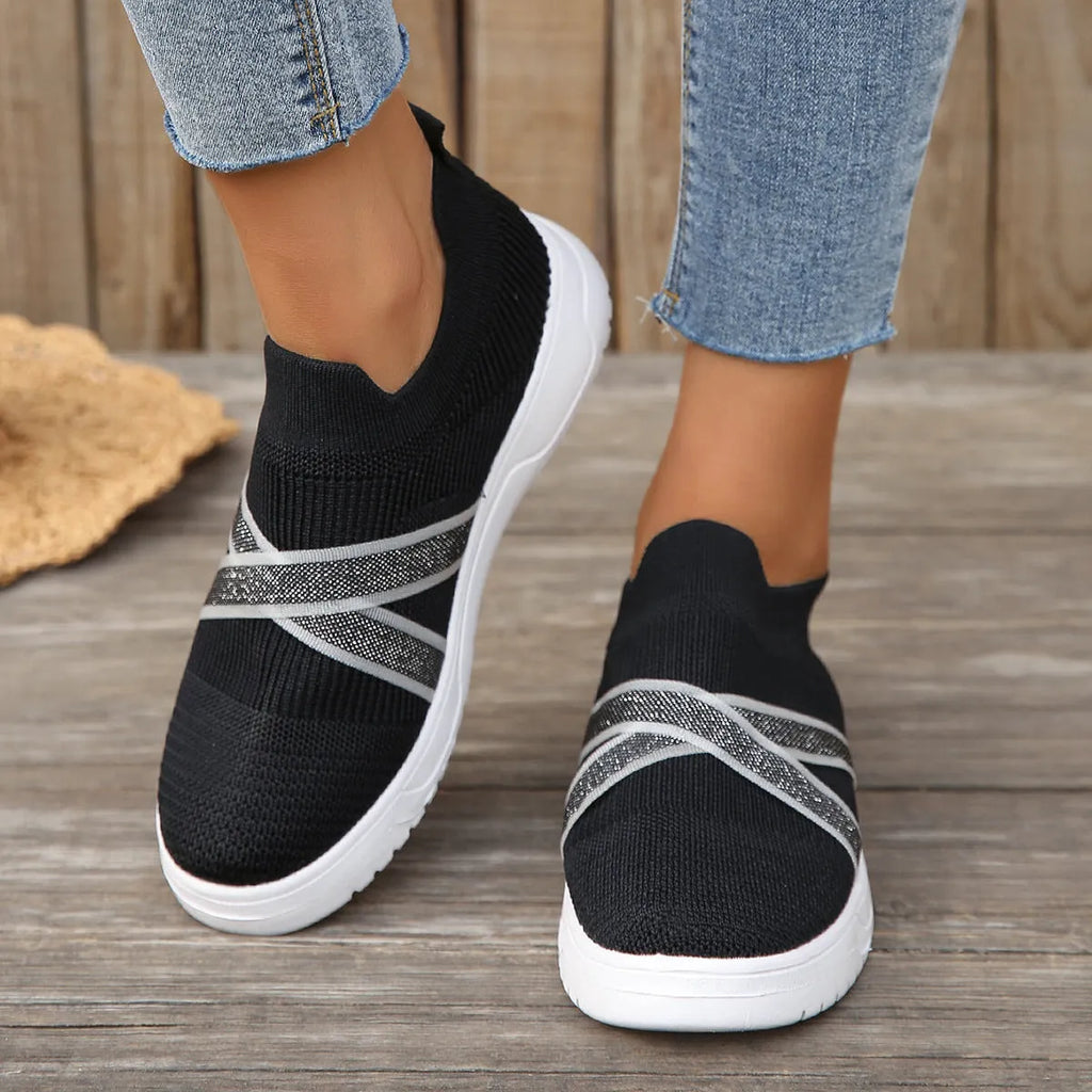 Black women's flat casual shoes with flyknit mesh upper and tassel detail on a flat rubber sole.