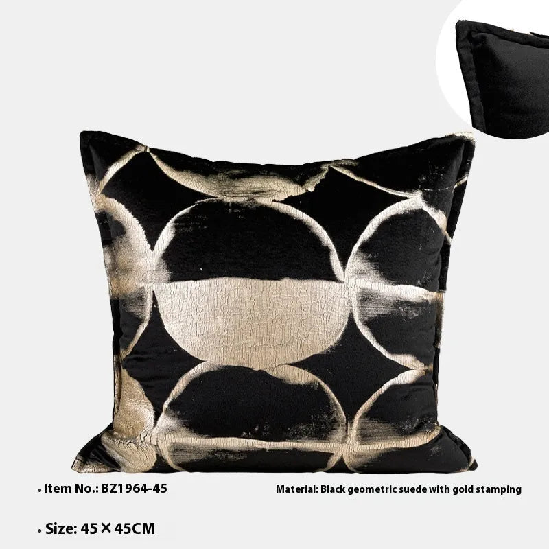 Black and gold abstract pattern decorative square and waist pillow cushions on a grey sofa.