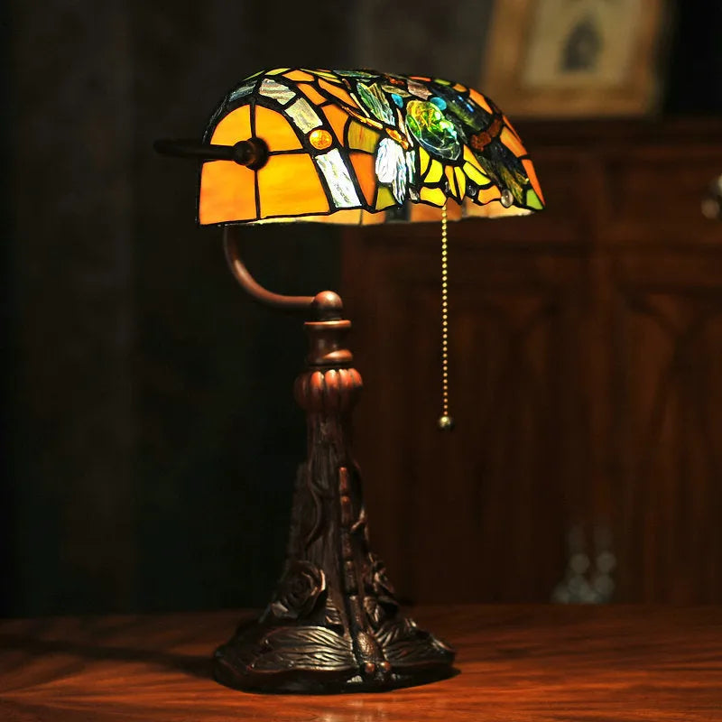 A 10-inch tall Tiffany-style table lamp with a stained glass shade on a resin base, shown on a desk.