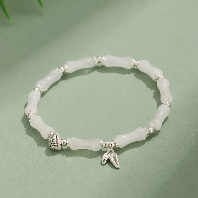 Women's green aventurine crystal bracelet with bamboo, strawberry quartz, and jade beads on wrist.