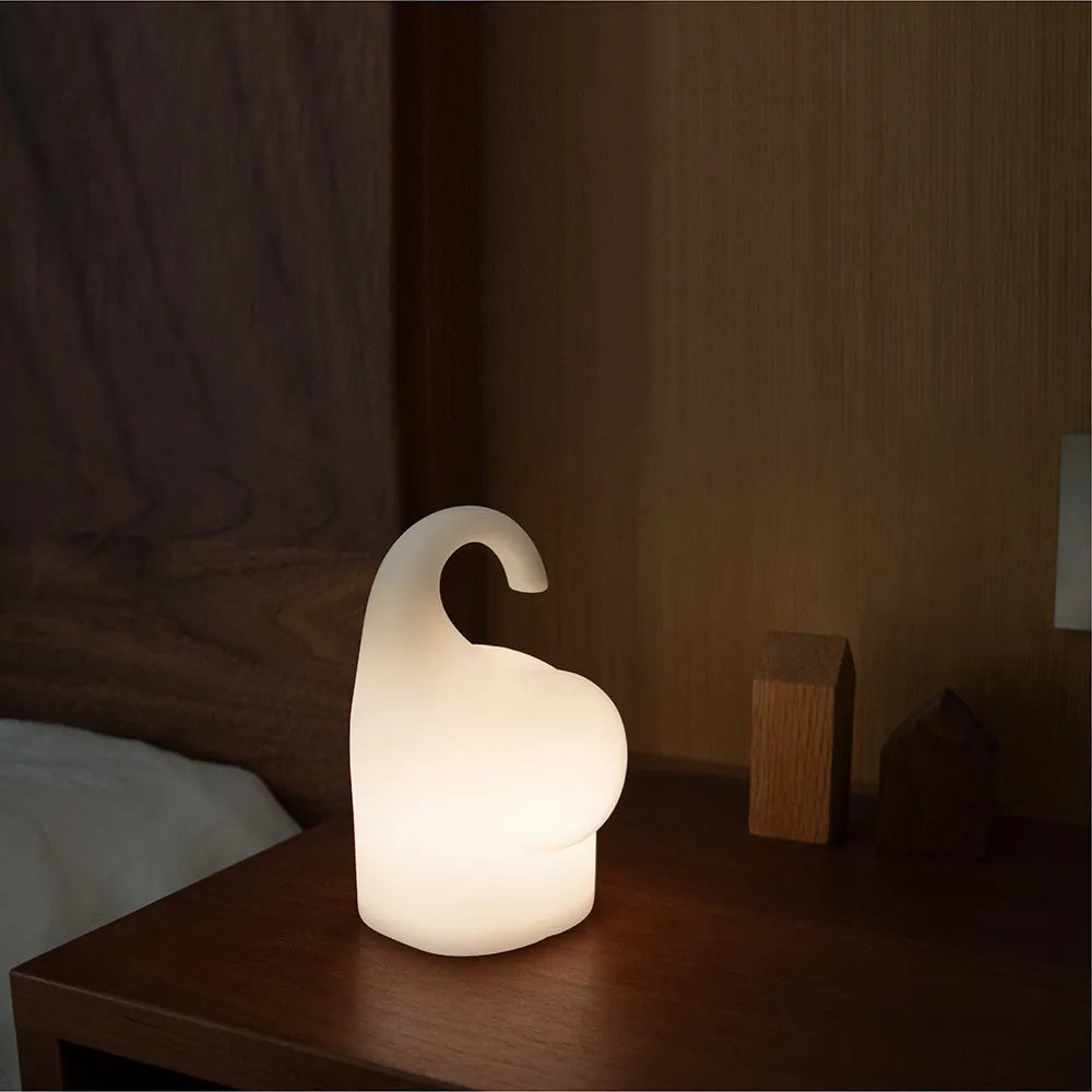 White silicone elephant-shaped night light with a warm glow on a bedside table.
