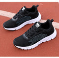 Low-top black and white running sneakers with cross-strap detail and flat MD sole.