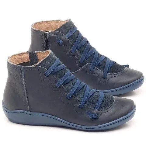 Women's black casual ankle boots with a round toe and a low wedge heel on a wooden floor.
