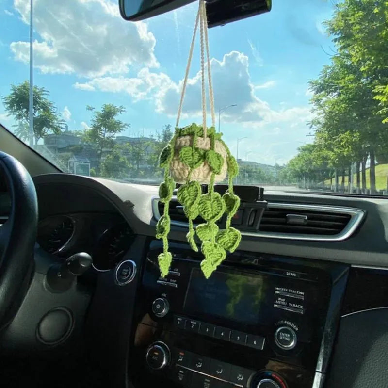 Green and white crocheted wool car plant decoration with a white hanging rope.