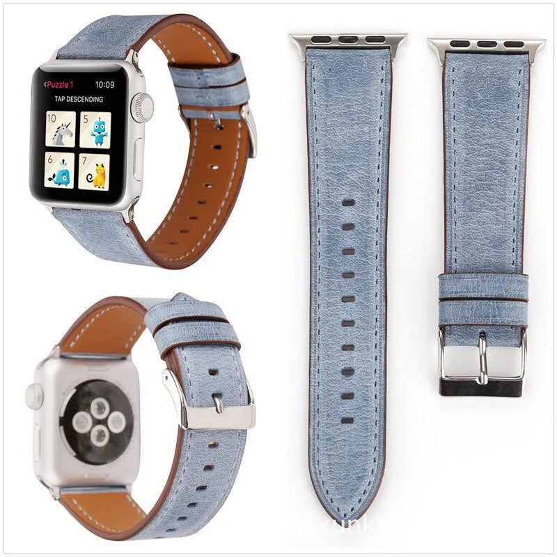 Leather watch strap with a metal folding buckle on a wooden surface.