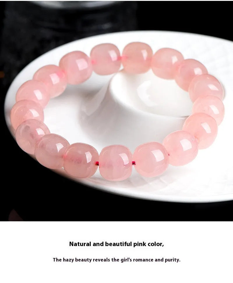 Pink natural crystal bracelet with barrel-shaped beads on a wrist.
