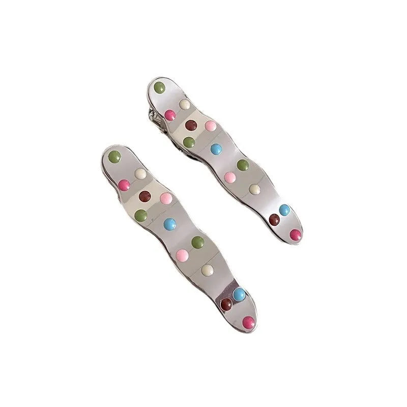 Two electroplated metal duckbill hairpins with hollow heart, star, and wave cut-out designs in silver tone