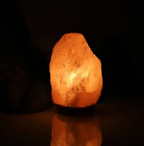 Natural rock salt crystal lamp with warm glow on bedside table, compact 10-11cm diameter