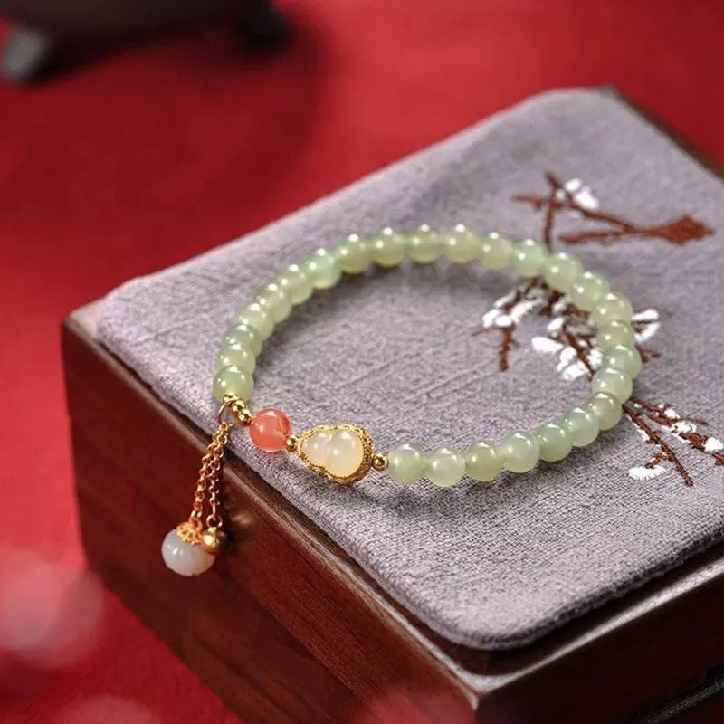 Qingshui jade women's bracelet with gold plated beads and a fu character charm.
