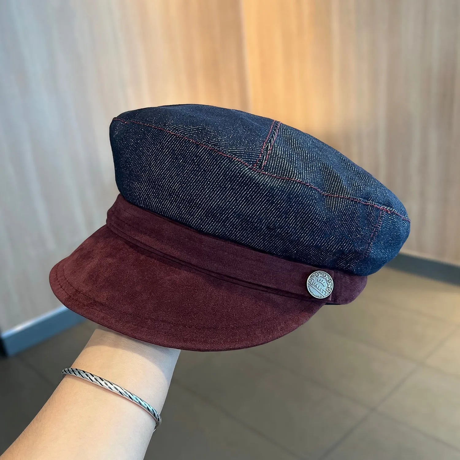 Dark blue denim octagonal newsboy flat cap with an adjustable strap, shown with a contrasting brown brim.