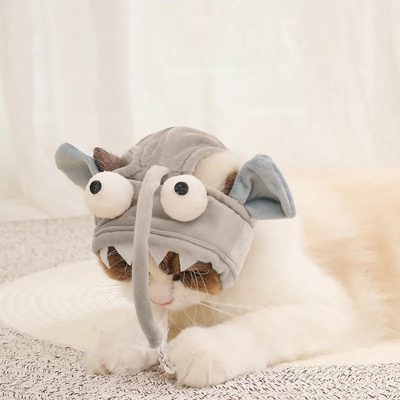 Grey dinosaur-themed cat headband toy with big eyes, a feather teaser, and an adjustable strap for hands-free play.