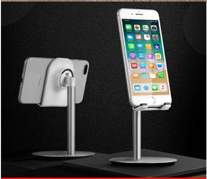 Silver metal computer phone holder stand for smartphones and tablets on a desktop.