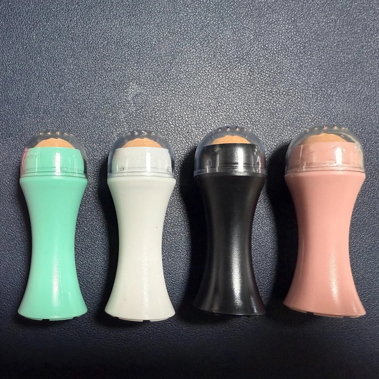 Volcanic stone facial roller for oily skin control in black, green, pink, or white.