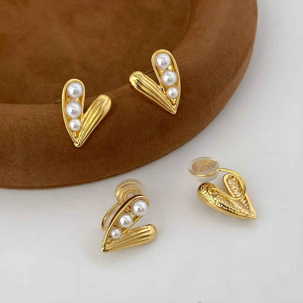 Heart-shaped pearl earrings in copper with electroplated finish, shown as ear clips or ear studs for women.