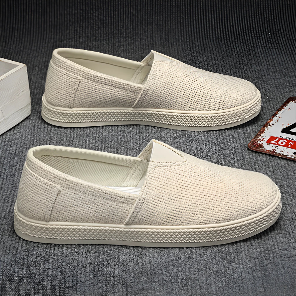 Men's beige canvas slip-on shoes with round toe and PVC sole on neutral background