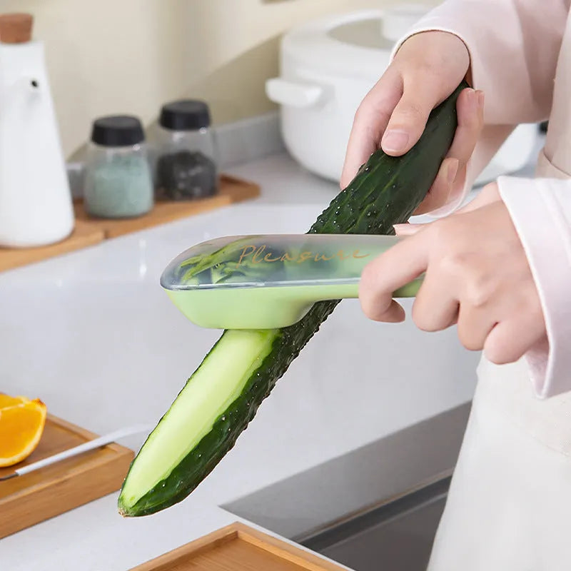 Dark green kitchen peeler with plastic handle inside its clear storage tube on a wooden surface.