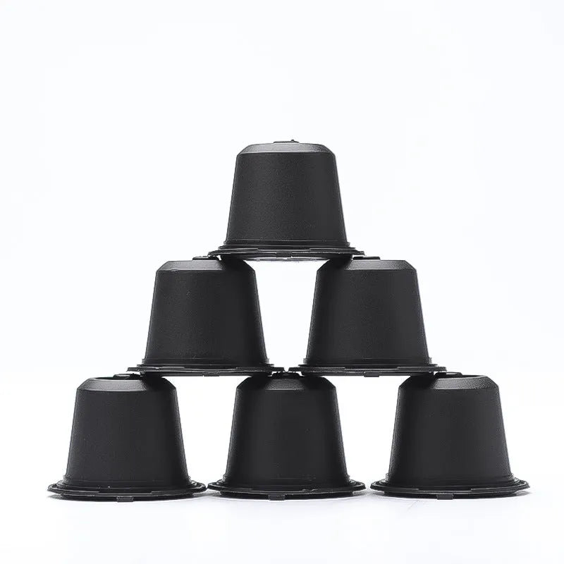 Six plastic coffee filter cups in black, red, and brown with a spoon, reusable shell capsule design for home brewing