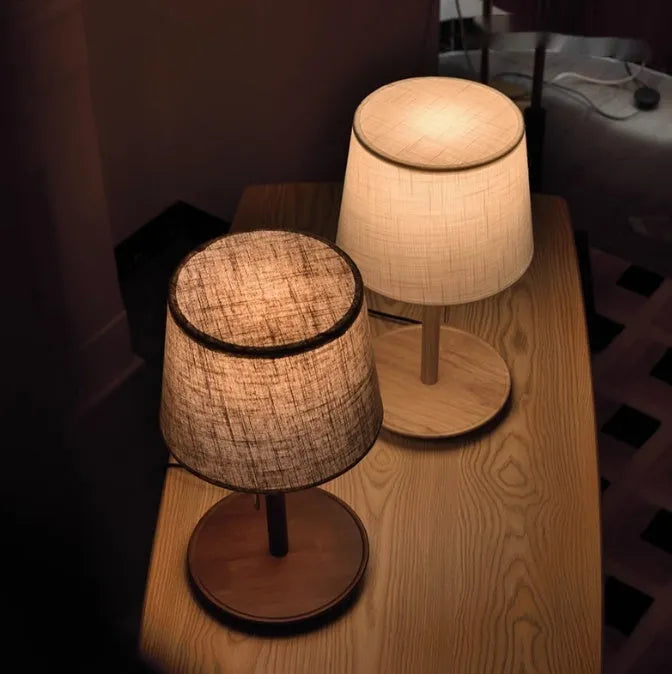 Walnut coloured solid wood bedside lamp with a white fabric lampshade and a cable switch