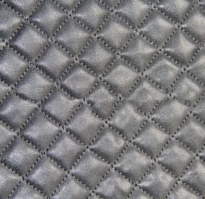 Black quilted automotive seat cover made of PU and polyester fabric with plastic attachment hooks.