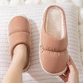 A pair of thick-soled house slippers with an artificial leather upper and plush lining, shown in a selection of colours.