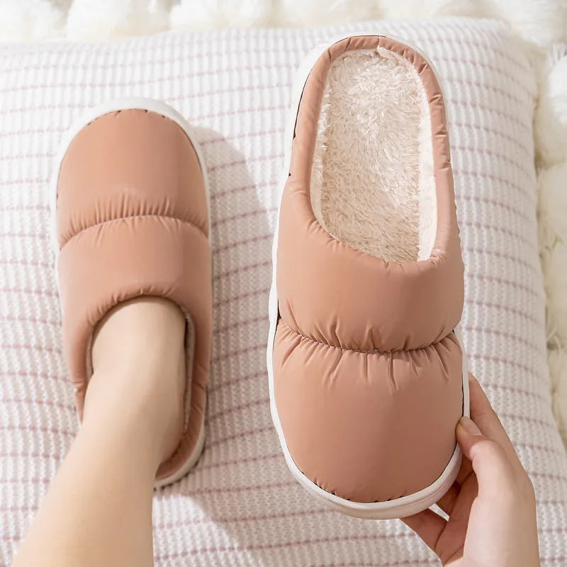 A pair of thick-soled house slippers with an artificial leather upper and plush lining, shown in a selection of colours.