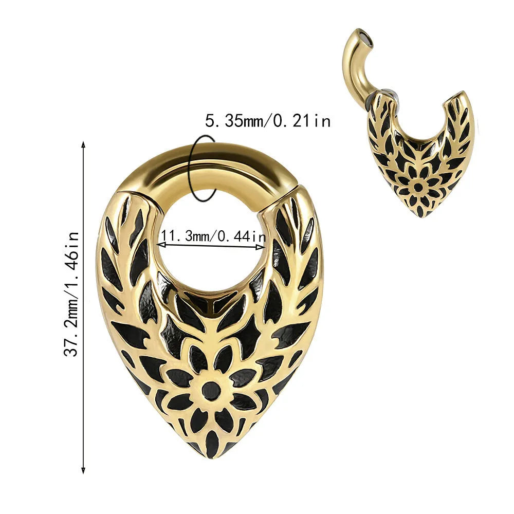 A single stainless steel teardrop-shaped ear extender for stretched lobes, showing a totem pattern on its face.