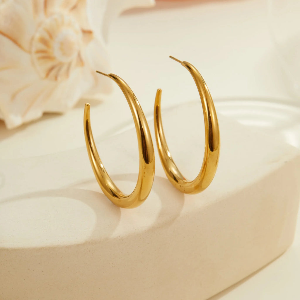 A pair of round titanium steel hoop earrings with an 18K gold plated finish, shown in large and small size options.
