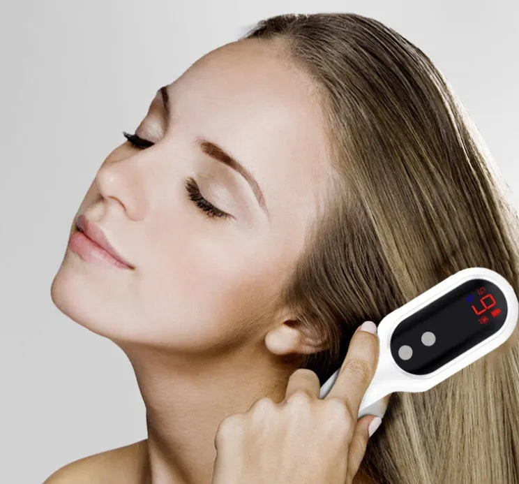 White electric head massager comb with red and blue light therapy, magnetic contacts, and LED display on a clean background