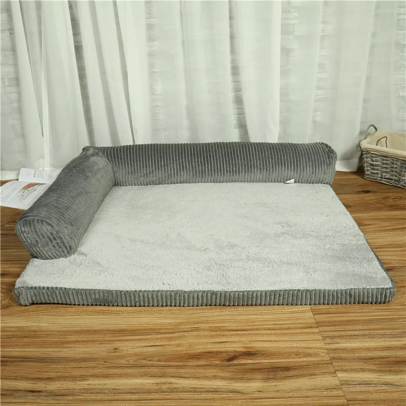 A corduroy dog sofa bed with a raised bolster side, shown in a grey colour on a wooden floor.