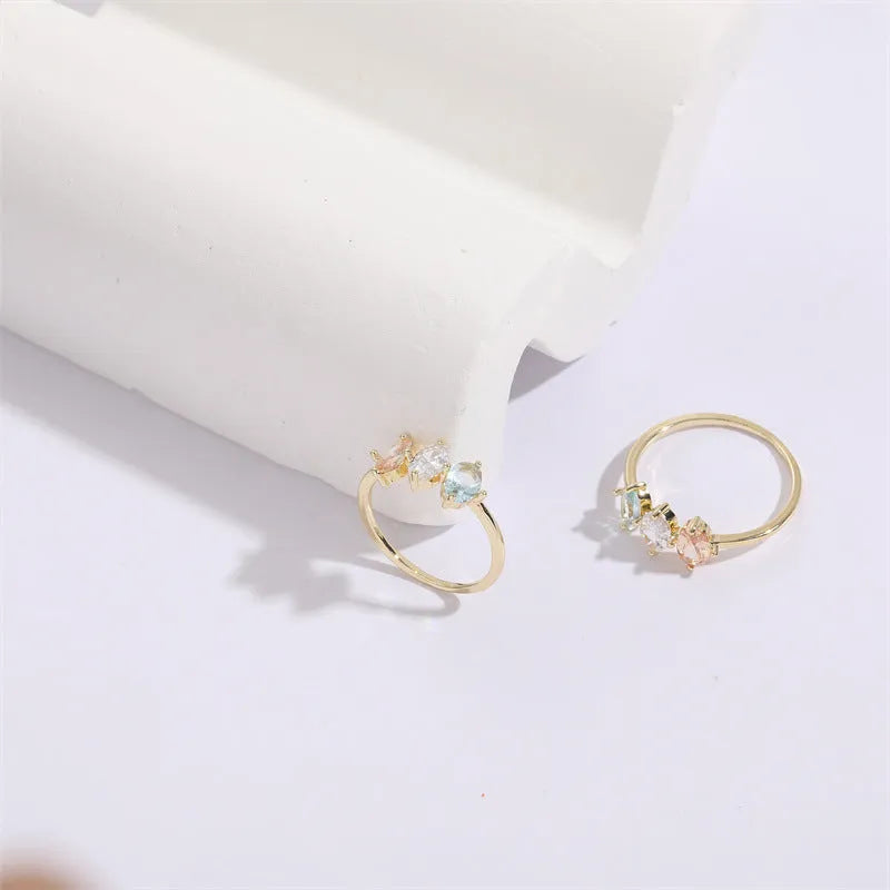 Geometric copper ring with a triangular tricolour zircon birthstone in a horse eye design, showing 14k gold electroplated finish.
