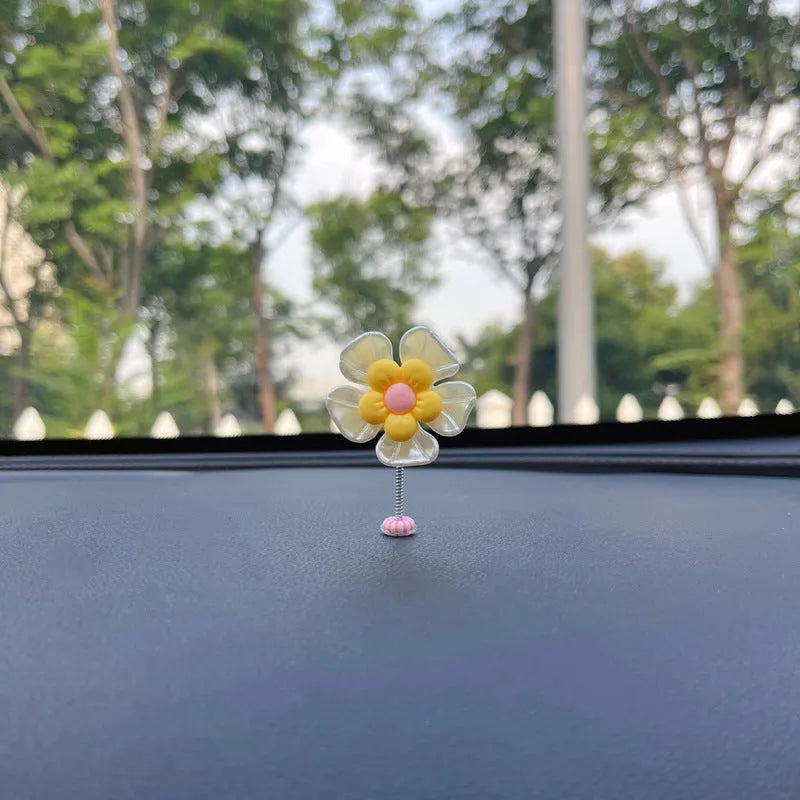Small colourful plastic car decoration shaped like a swing, shown in blue, on a car dashboard.