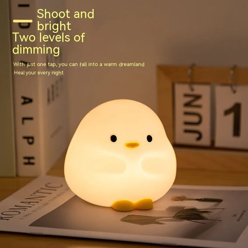 Cute duck-shaped silicone LED night lamp with touch sensor and warm glow on a bedside table